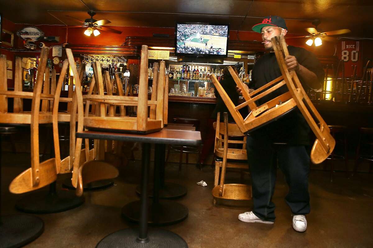 Chris Nobida brings in outside furniture during closing time at 7 miles house, a sports bar founded in 1853, on Wednesday, April 28, 2017, in San Francisco, Calif.