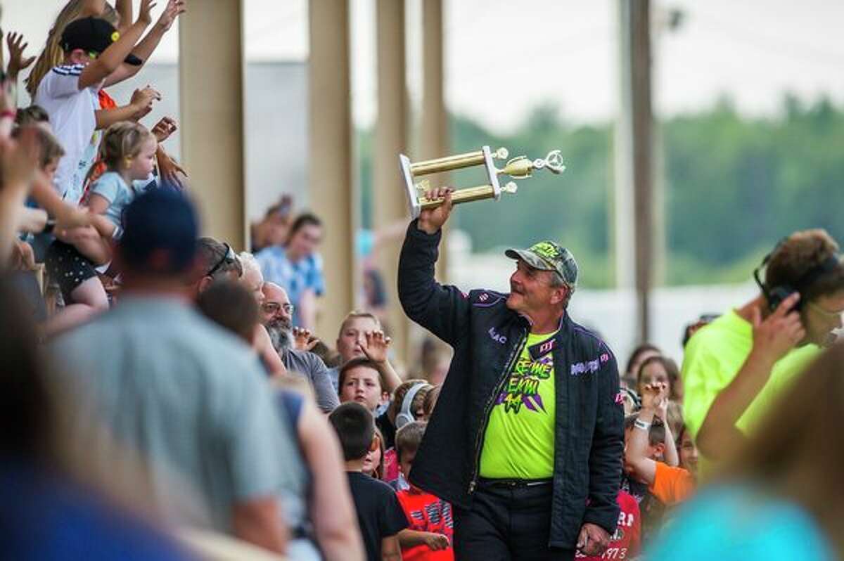 Monster truck driver Mac Plecker of Georgia carries one of his trophies before giving it to a child during the rally on Wednesday. (Katy Kildee/kkildee@mdn.net)
