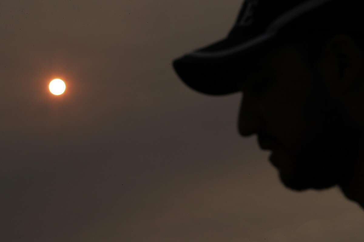 Firefighter Thomas Harre stands silhouetted by the sun, colored by the heavy smoke in the air, at the Incident Command Post before heading out to the Mendocino Complex Fire in Ukiah, Calif., on Tuesday, August 14, 2018.