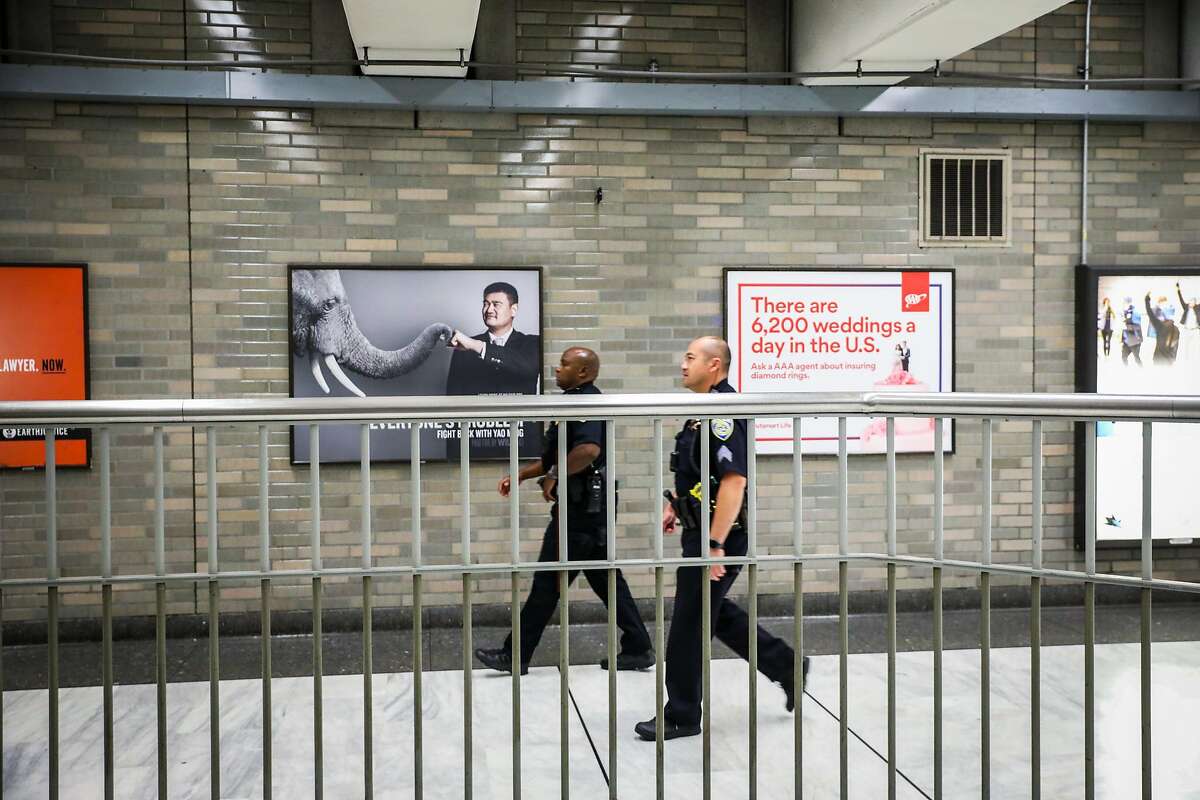 Police officers survey the BART station at Civic Center as they pass a gate that has recently been installed to deter fare evasion in San Francisco, California, on Thursday, Aug. 16, 2018.