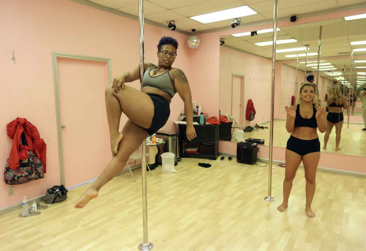 Soft Sensuous Moves pole fitness student Shanel Watkins practices a move while instructor Carla Wetzel encourages her. Watkins is a full-time student at the University of Texas at San Antonio and has been in the pole-dancing class for eight months.
