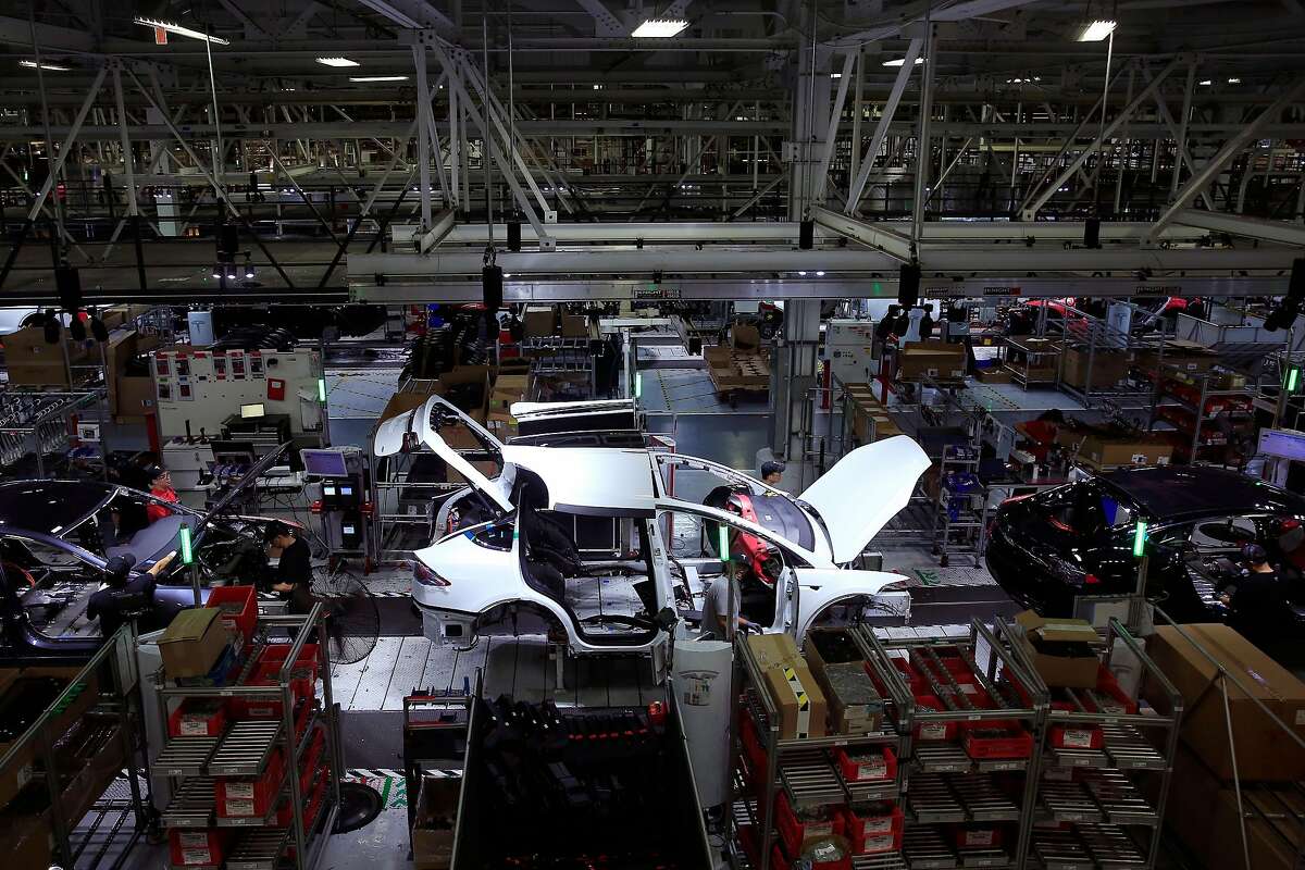 A Tesla Model X is worked on a factory line with Tesla X's and Tesla S's at the Tesla factory on Wednesday, July 18, 2018 in Fremont, Calif.