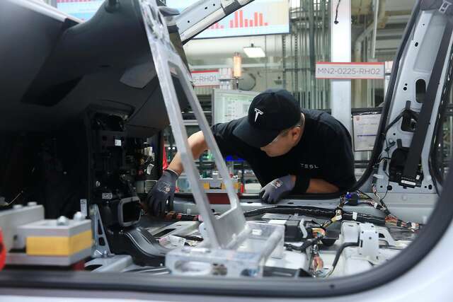 A production associate works on a Tesla Model 3 at the Tesla factory on Wednesday, July 18, 2018 in Fremont, Calif.