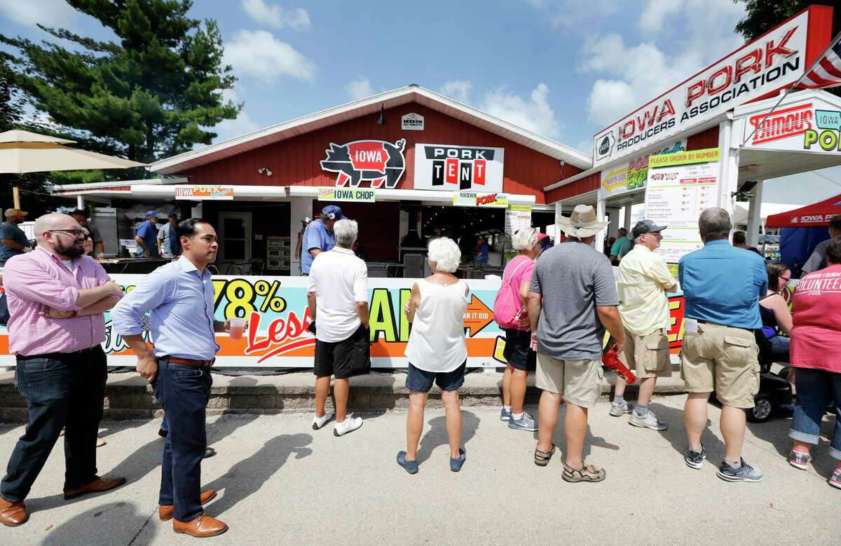 Former Housing and Urban Development Secretary Julian Castro, second from left, waits in line at the Iowa Pork Producers tent during a visit to the Iowa State Fair, Friday, Aug. 17, 2018, in Des Moines, Iowa. (AP Photo/Charlie Neibergall)