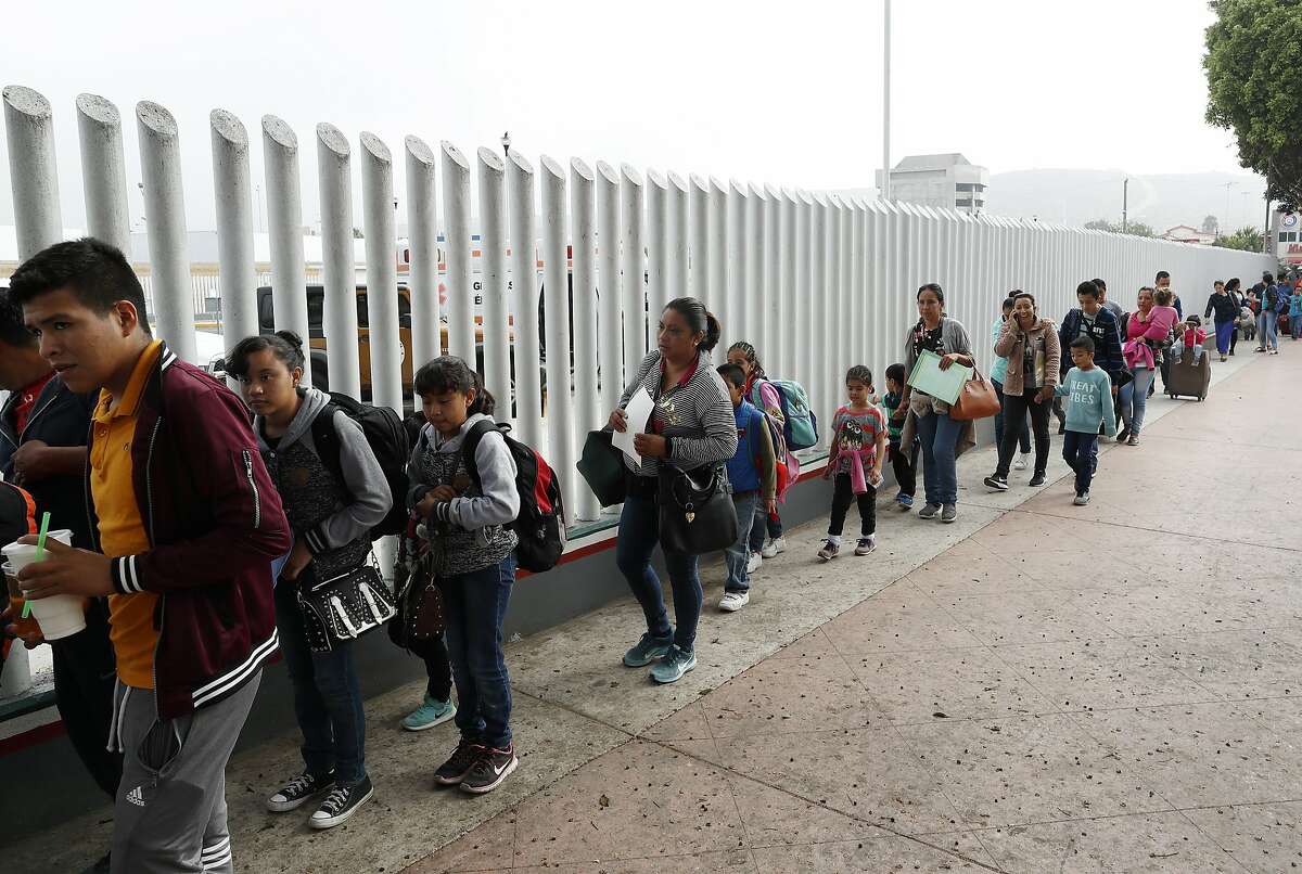 FILE - In this Thursday, July 26, 2018 photo people line up to cross into the United States to begin the process of applying for asylum near the San Ysidro port of entry in Tijuana, Mexico. A federal judge has extended a freeze on deporting families separated at the U.S.-Mexico border, giving a reprieve to hundreds of children and their parents to remain in the United States. U.S. District Judge Dana Sabraw said in his order Thursday, Aug. 16, 2018, that "hasty" deportation of children after reunification with their parents would deprive them of their right to seek asylum. (AP Photo/Gregory Bull,File)