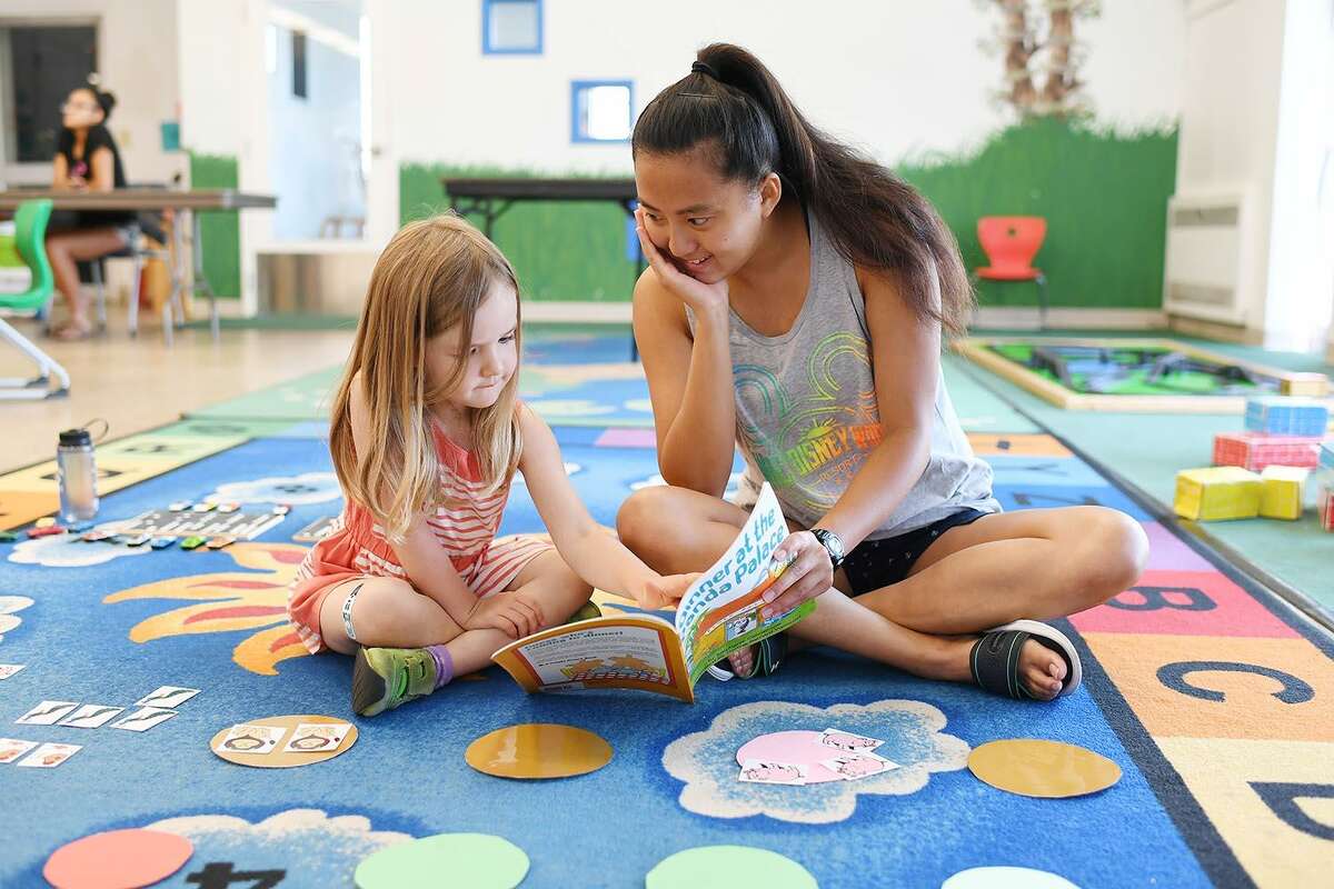 Wesleyan student Emma Distler plays an interactive reading and counting game with 4-year-old Isabella at Russell Library July 31.