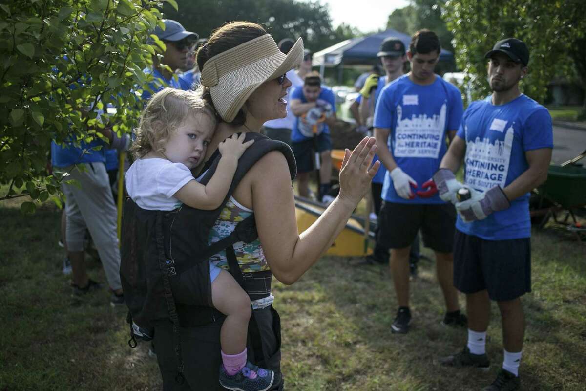 Caroline Attwood, steward of Jefferson Community Garden, carries 1-year-old daughter Michelle on her back as she gives volunteers guidance.