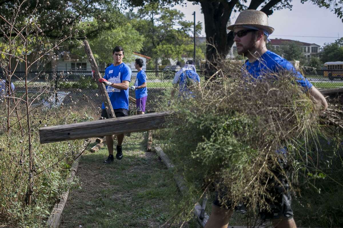 Eduardo Torres carries wood to be thrown away at the Jefferson Community Garden as part of St. Mary's University biannual service day Aug. 18, 2018.