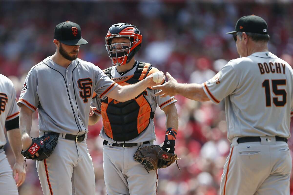 San Francisco Giants starting pitcher Andrew Suarez, left, is pulled from the game by manager Bruce Bochy, right during the third inning of a baseball game against the Cincinnati Reds, Sunday, Aug. 19, 2018, in Cincinnati. At rear is Giants catcher Nick Hundley. (AP Photo/Gary Landers)