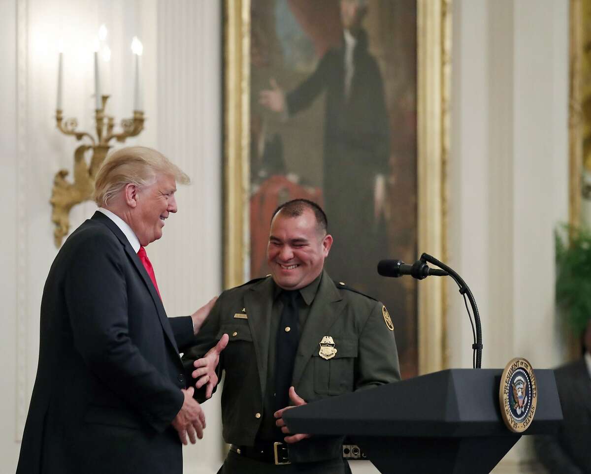 President Donald Trump, left, shakes hands with Customs and Border Patrol agent Adrian Anzaldua, during an event to salute U.S. Immigration and Customs Enforcement (ICE) officers and U.S. Customs and Border Protection (CBP) agents in the East Room of the White House in Washington, Monday, Aug. 20, 2018. (AP Photo/Alex Brandon)