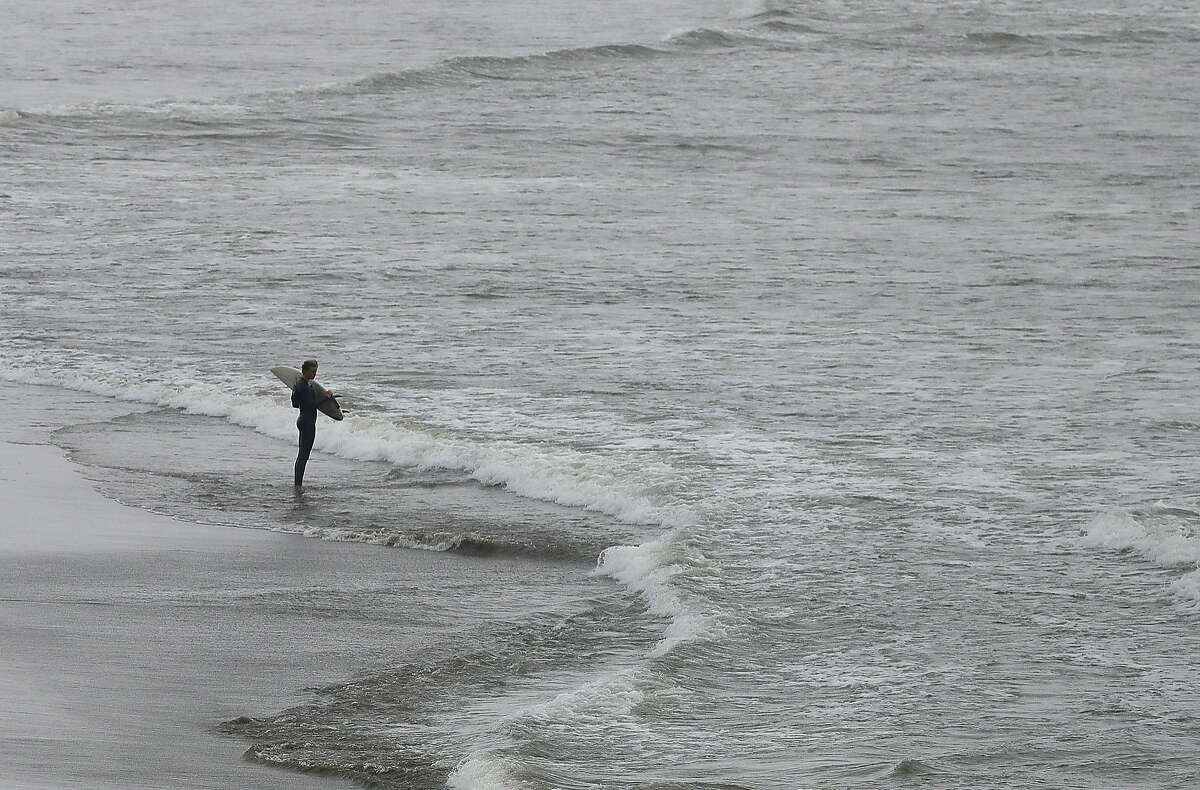 A surfer holds his board at Ocean Beach in San Francisco, Monday, Aug. 20, 2018. California Gov. Jerry Brown announced Monday, Aug. 20, 2018 that he signed a bill making surfing the official state sport. (AP Photo/Jeff Chiu)