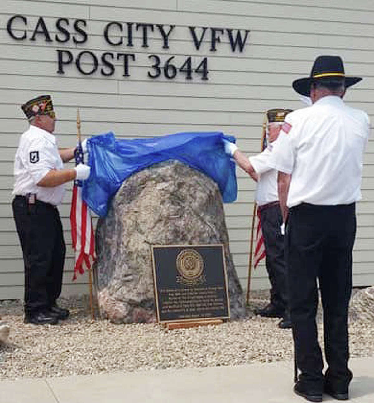 A commemorative plaque in front of the Cass City VFW Post 3644 honoring those who served in the Vietnam War was dedicated Saturday. Unveiling the monument are, from left, John Newton and Nick Pink, while VFW Commander Joe Merchant stands in front.