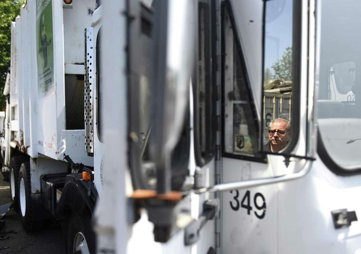 Fleet Manager Michael Scacco is reflected in the side mirror as he shows one of the garbage trucks that will be used for leaf collection at the Stamford Fleet Maintenance center in Stamford, Conn. Tuesday, Aug. 21, 2018. As a cost-saving measure, Stamford will deploy three garbage trucks to collect bagged leaves instead of the using the large leaf "vacuums" as in the past. The trucks were used as backups before and are getting standard maintenance done to get their capacities on par with the rest of the fleet.