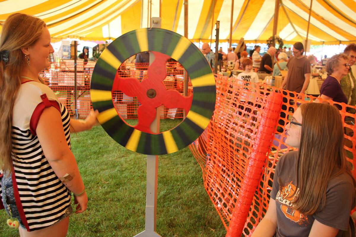 Jacie Tyrrell, 14, of Ubly, spins a game wheel while Lindsey Gosdzinski, 16, of Ubly, looks along, at Sunday’s Saint Isidore Summer Festival at Saint Mary Catholic Church in Parisville.