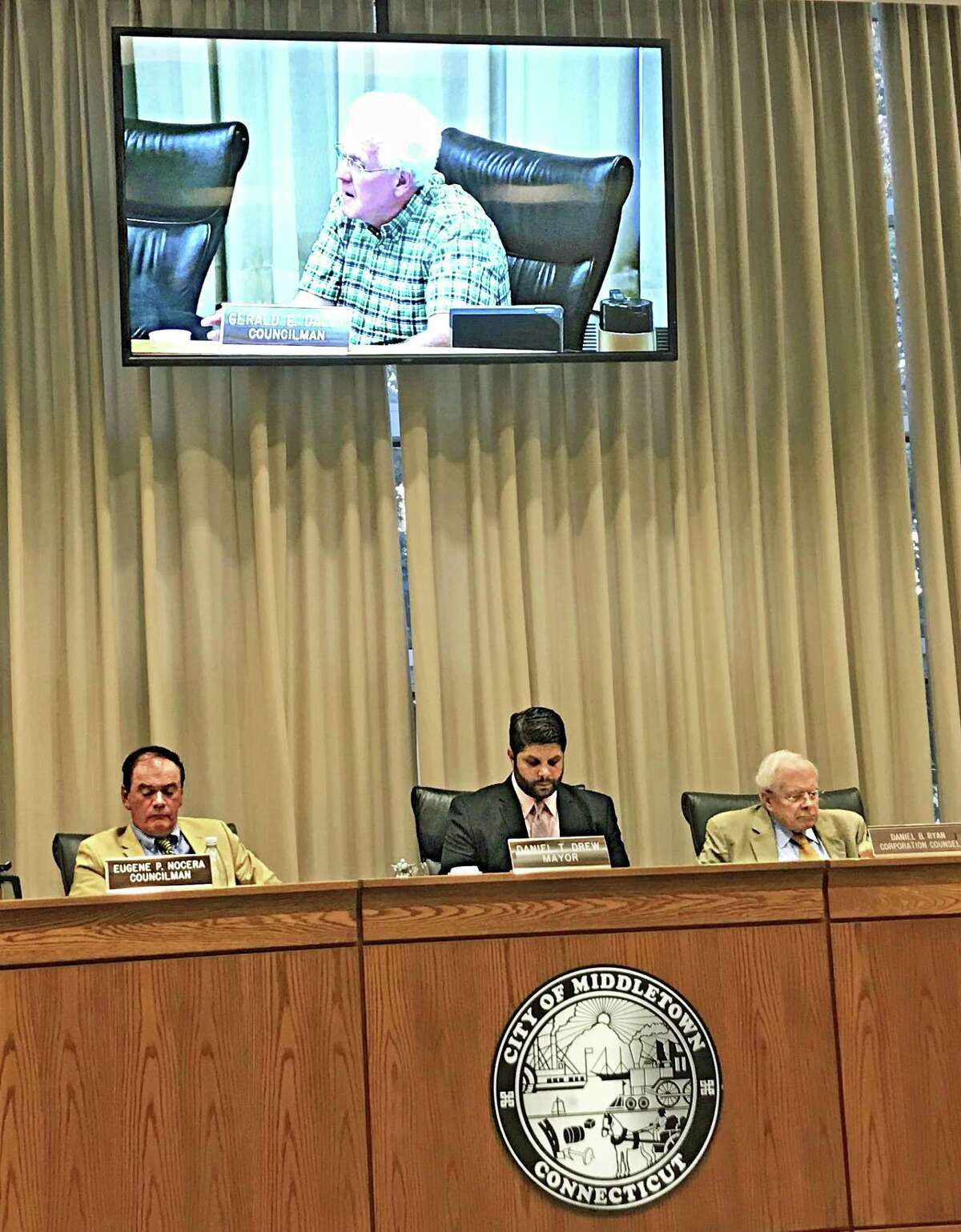 From left, Middletown Common Councilman Gene Nocera, Mayor Dan Drew, and corporate counsel Daniel Ryan hear from the independent investigator charged with conducting a report into a complaint lodged against Drew by a Board of Education employee at the Aug. 13 meeting. On screen is Councilman Gerry Daley.