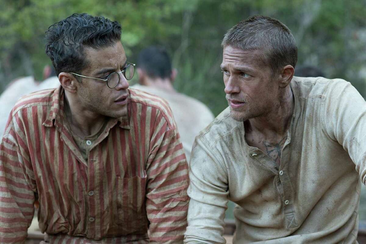 Rami Malek plays Dega and Charlie Hunnam is Papillon, fellow prisoners in the movie “Papillon.”