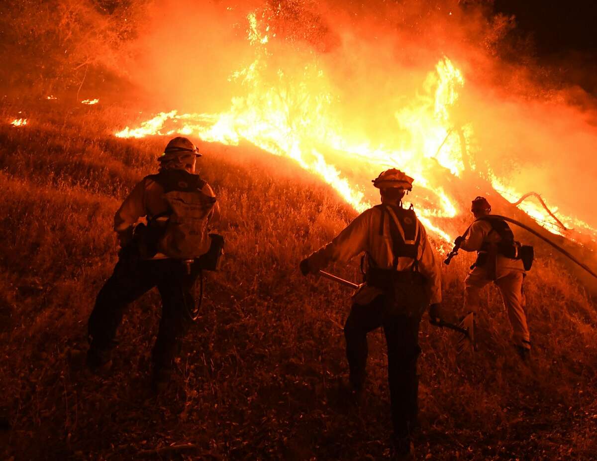 Firefighters conduct a controlled burn to defend houses against flames from the Ranch Fire, part of the Mendocino Complex Fire.