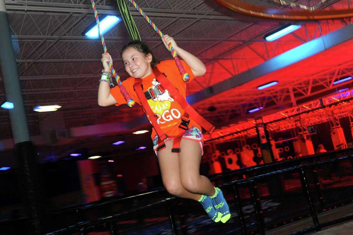 Maggie Nevis, of Orange, swings while riding down a zip line at the Urban Air Trampoline & Amusement Park, in Orange, Conn. Aug. 23, 2018.