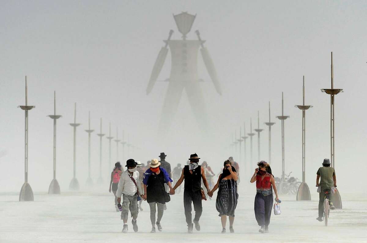 Burning Man participants walk through dust at the annual Burning Man event on the Black Rock Desert of Gerlach, Nev., on Friday, Aug. 29, 2014.