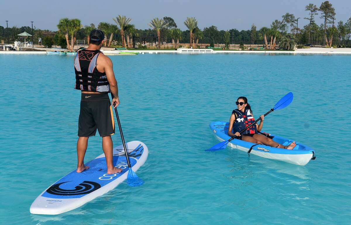 Ally Brown, right, of Katy, and Carlos Sepulveda, left, both actors with Pastorini-Bosby Talent Agency of Houston, work their kayak stand-up paddle board on the water during the grand opening of the Crystal Lagoon in the Balmoral community in Humble on August 23, 2018.