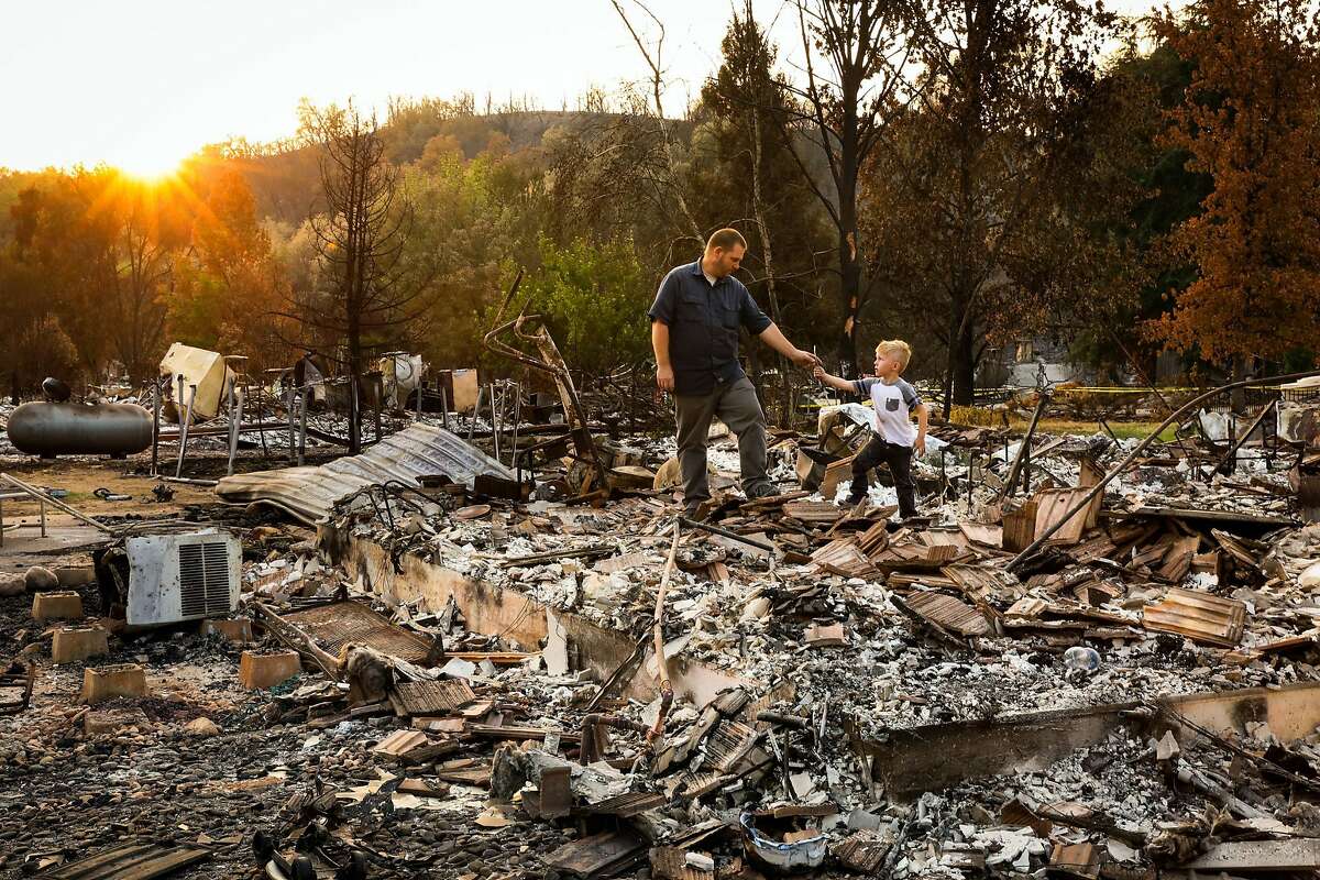 Daniel Wood, 5, (right) shows his grandfather Matthew Schjoth a wrench he found as they look through the destroyed remains of their home on Harlan Drive in Redding, California, on Thursday, Aug. 23, 2018.