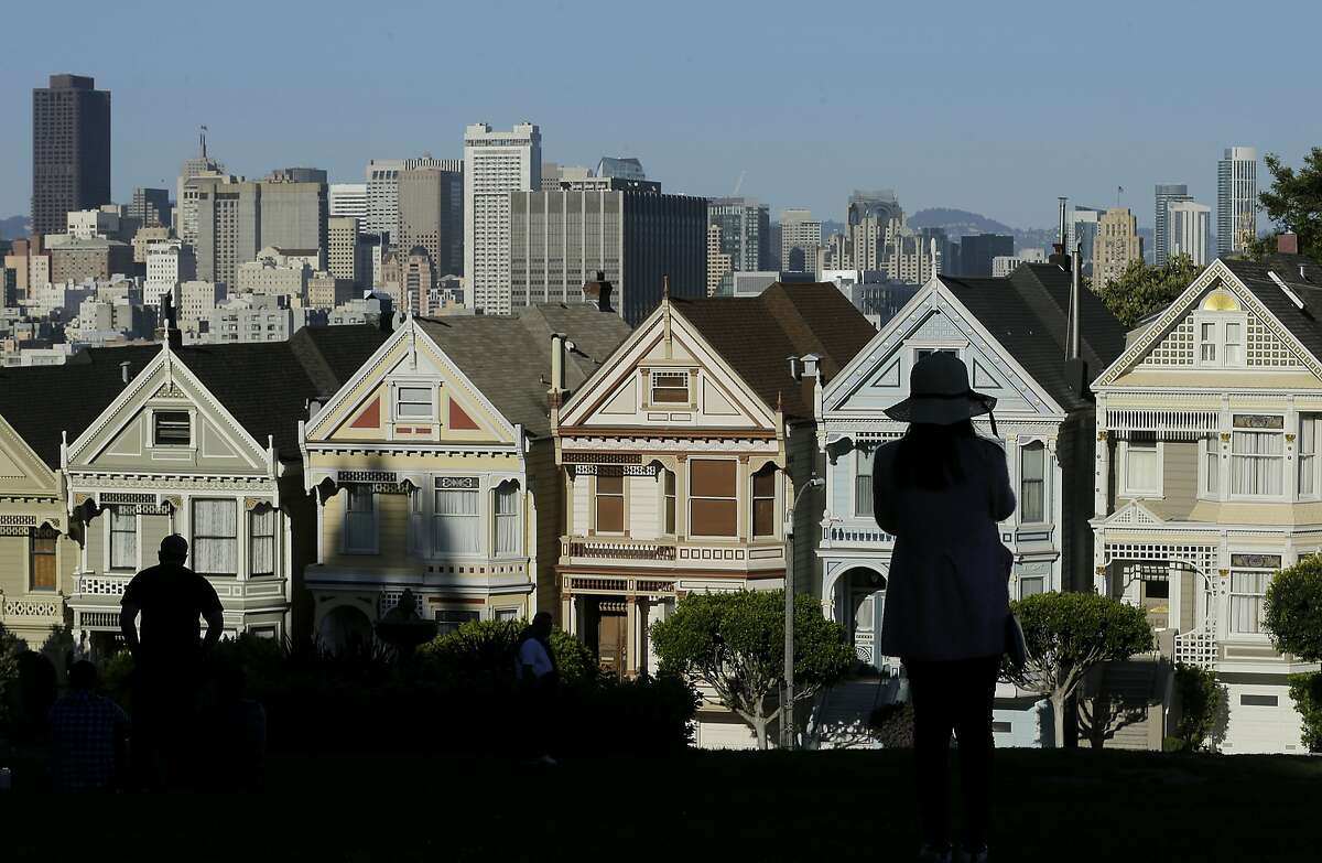 FILE- In this April 15, 2016, file photo a woman looks toward the "Painted Ladies," a row of historical Victorian homes, with the San Francisco skyline at rear at Alamo Square Park in San Francisco. The Trump administration announced new rules Thursday, Aug. 23, 2018, aimed at preventing residents in high-tax states from avoiding a new cap on widely popular state and local tax deductions. (AP Photo/Jeff Chiu, File)