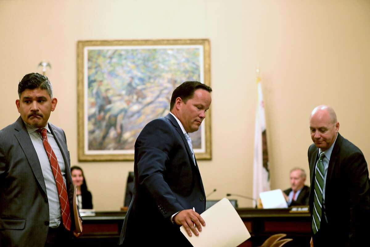 (Left to right) Rudy Reyes, vice president and associate general counsel of the western region at Verizon, David Hickey, executive director of business sales and Wes Senechal, vice president - government sales, exit their seats after answering questions by the Assembly Select Committee in Sacramento.