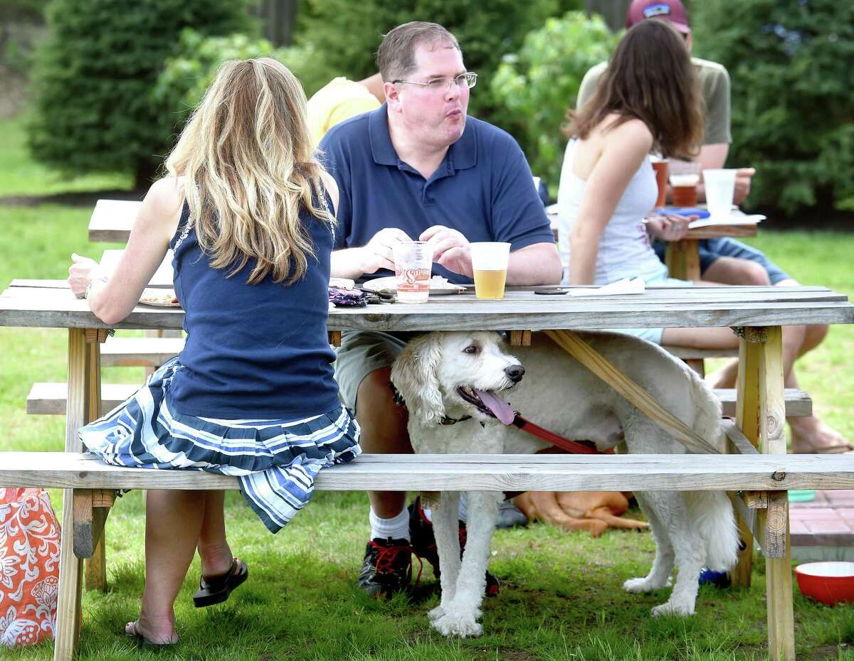(Arnold Gold-New Haven Register) Colleen Leary (left) and her husband, Brian (center) of Milford enjoy pizza and Sixpoint Brewery beer to celebrate her birthday with their golden doodle, Bailey, during the Beers for Beasts event at The Hops Company in Derby to benefit the Shelton Animal Shelter and the Friends of New Haven Animal Shelter on 4/29/2017.