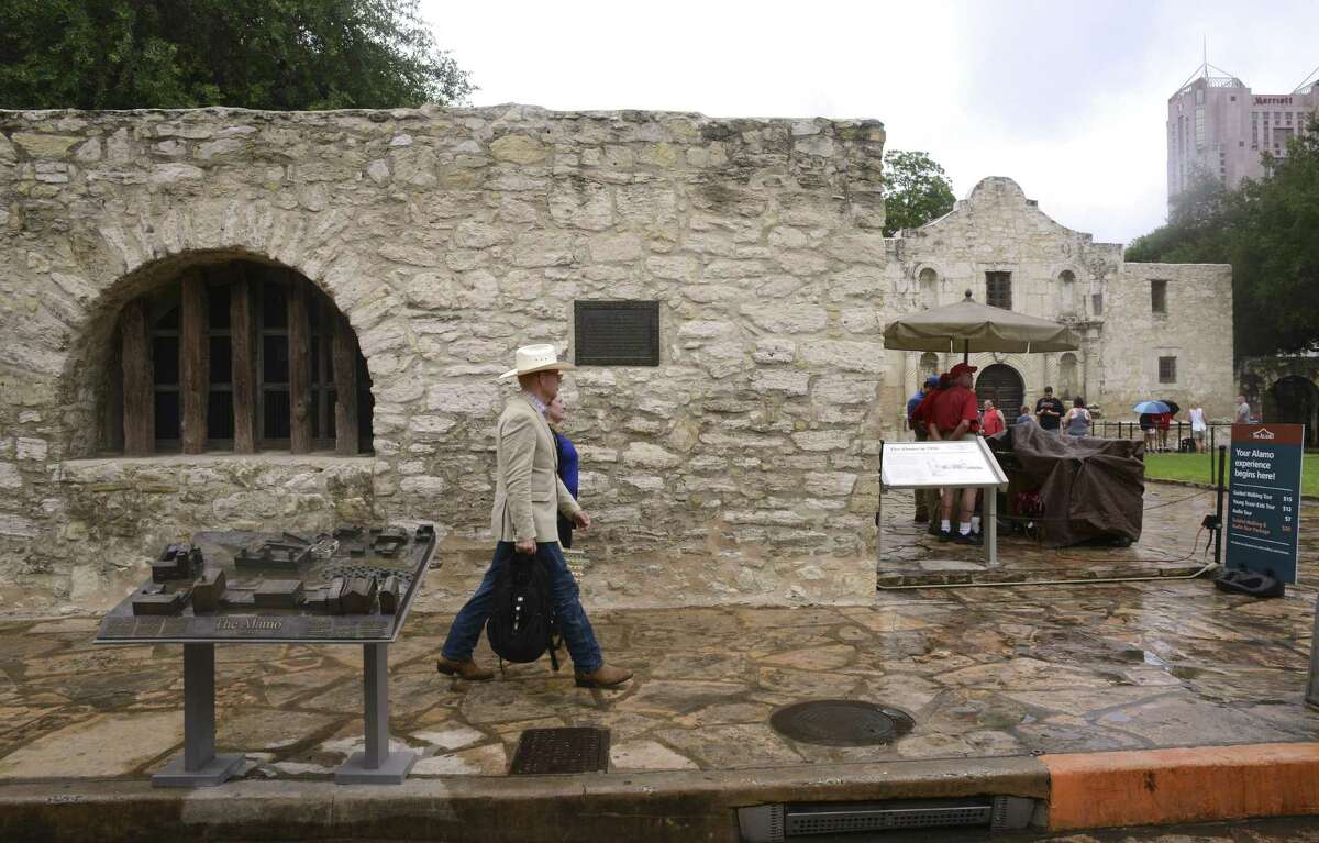 People walk by a bronze panel depicting the evolution of the Alamo from Mission San Antonio de Valero in the 1700s to the military fort known as the Alamo. Several panels have been placed near the Long Barracks and were commissioned by musician Phil Collins, who is a collector of Alamo artifacts.