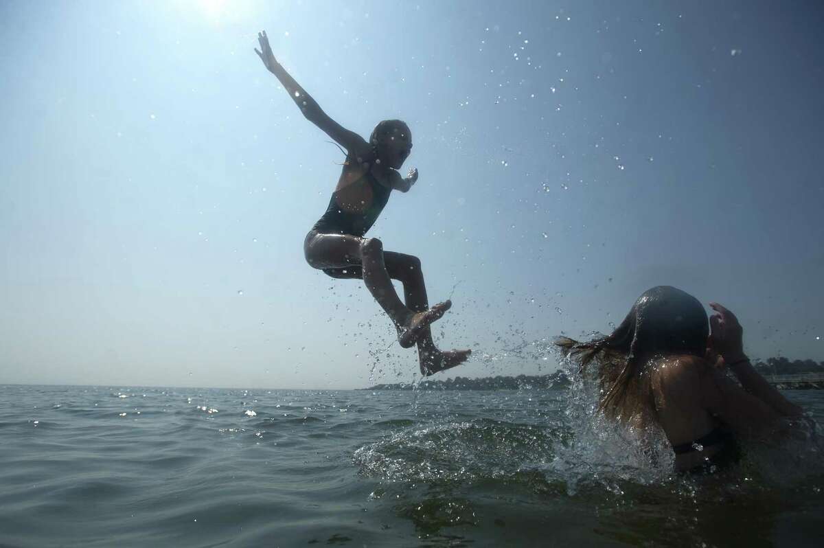 Nine-year-old Katerina Kucher, of Stamford, gets thrown into Wescott Cove while beating the heat at Cummings Park Beach in Stamford, Conn. on Tuesday, Aug. 28, 2018. Temperatures reached into the mid 90s.