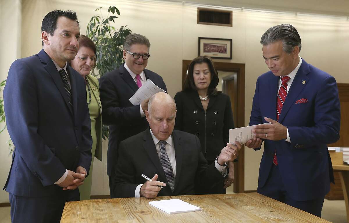 FILE PHOTO: Gov. Jerry Brown hands a copy of a bill to end bail he signed to Assemblyman Rob Bonta, D-Alameda, right, who along with state Sen. Bob Hertzberg, D-Van Nuys, third from right, co-authored the measure, during a signing ceremony, Tuesday, Aug. 28, 2018, in Sacramento, Calif. The bill makes California the first state to eliminate bail for suspects awaiting trial. Also seen are Assembly Speaker Anthony Rendon, D-Lakewood, left, Senate President Pro Tem Toni Atkins, D-San Diego, second from left, and California Supreme Court Chief Justice Tani Cantil-Sakauye, second from right, (AP Photo/Rich Pedroncelli)