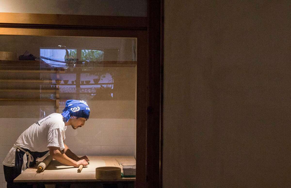 Koichi Ishii rolls out dough for traditional hand made soba noodles inside a sealed glass room in the early morning hours at Soba Ichi in Oakland, Calif. Wednesday, Aug. 15, 2018.