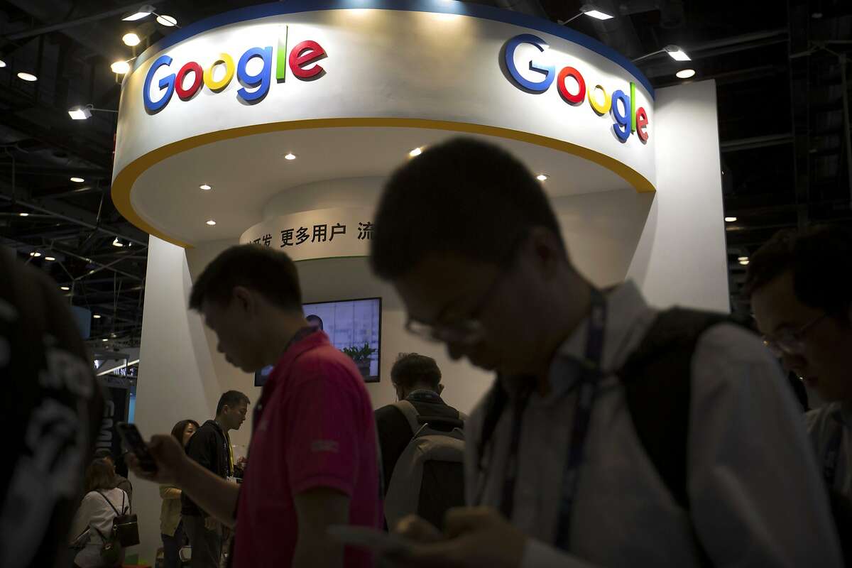 FILE - In this April 27, 2017, file photo, visitors use their smartphones in front of a booth for Google at the Global Mobile Internet Conference (GMIC) in Beijing. More than a dozen human rights groups have sent a letter dated Tuesday, Aug. 28, 2018, to Google urging the company not to offer censored internet search in China, amid reports it is planning to again begin offering the service in the giant Asian market. (AP Photo/Mark Schiefelbein, File)