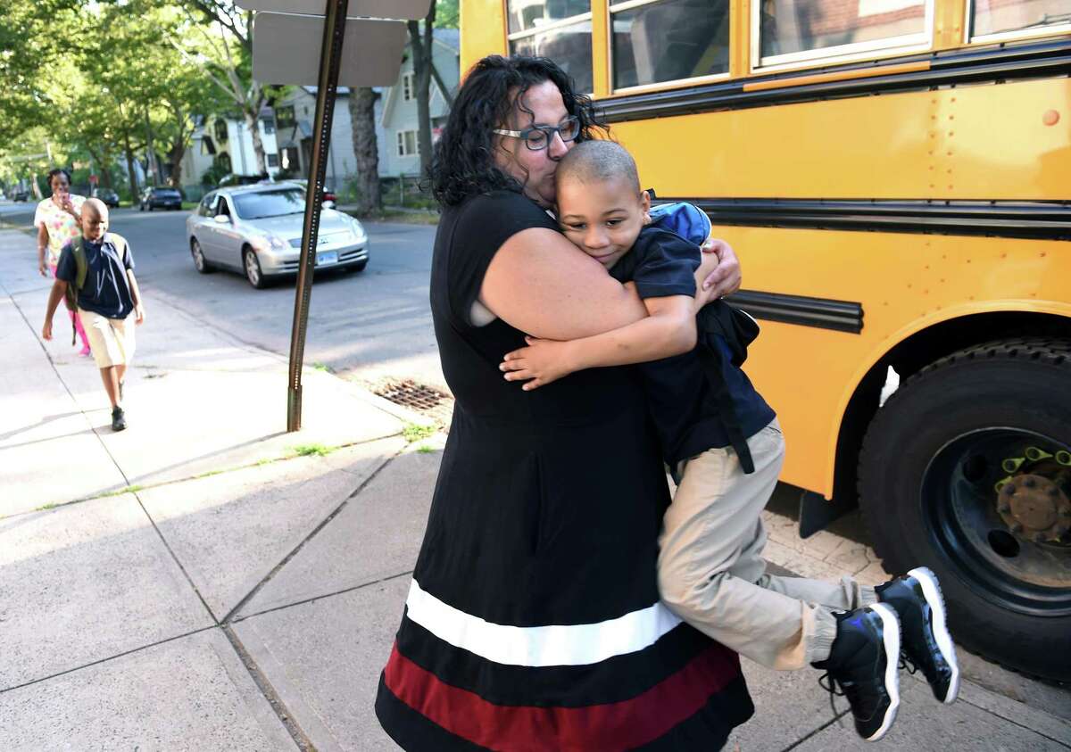 First grader Ahmir Woods jumped into the arms of leadership team member Lorrie Quirk as he arrives on the first day of school at Lincoln-Bassett Community School in New Haven Thursday.