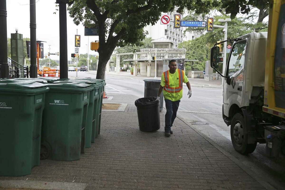 A City of San Antonio sanitation worker picks up recyclables at the corner of Losoya and East Commerce Streets on Aug. 12, 2018. Under the Alamo plan, Losoya would be widened to add a northbound lane, limiting the space available now for truck deliveries, garbage pickup and other services.