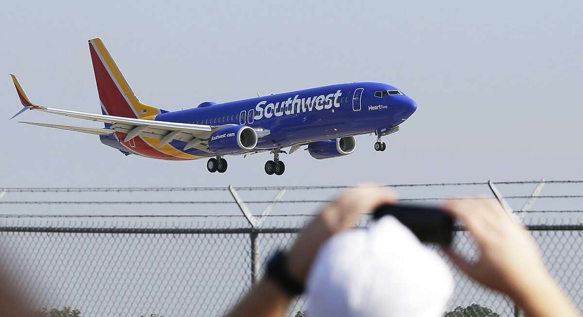 In this Sept. 8, 2014 file photo, a Southwest Airlines plane with a new paint job flies over Love Field in Dallas. On Monday, Oct. 13, 2014, Southwest will launch its first long-distance flights from its home base at Dallas Love Field to seven cities across the country, with eight more destinations next month. Such flights were prohibited until now by a longtime law that protected Dallas-Fort Worth International Airport by limiting flights from Love Field to a few nearby states. (AP Photo/LM Otero, File)