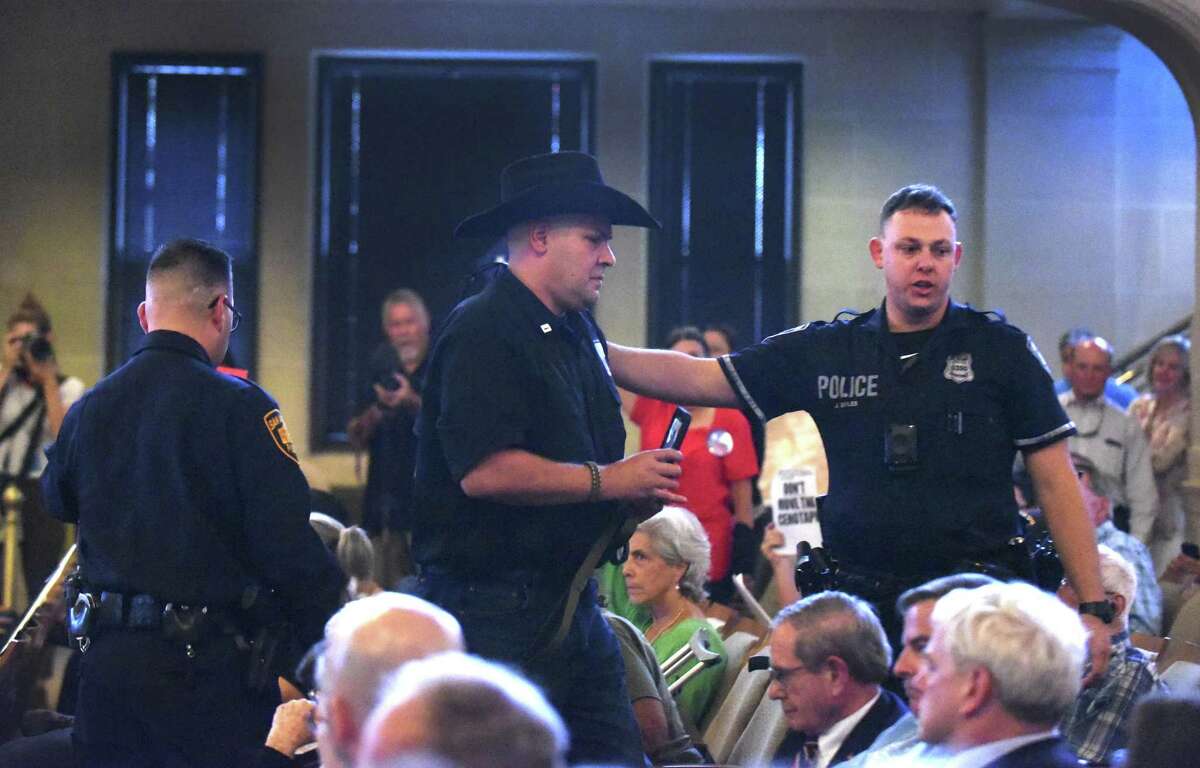 Brandon Burkhart, president of This Is Texas Freedom Force, is escorted out after an outburst during a meeting of the Alamo Citizen Advisory Committee, shortly before the panel voted in support of key changes to Alamo Plaza.