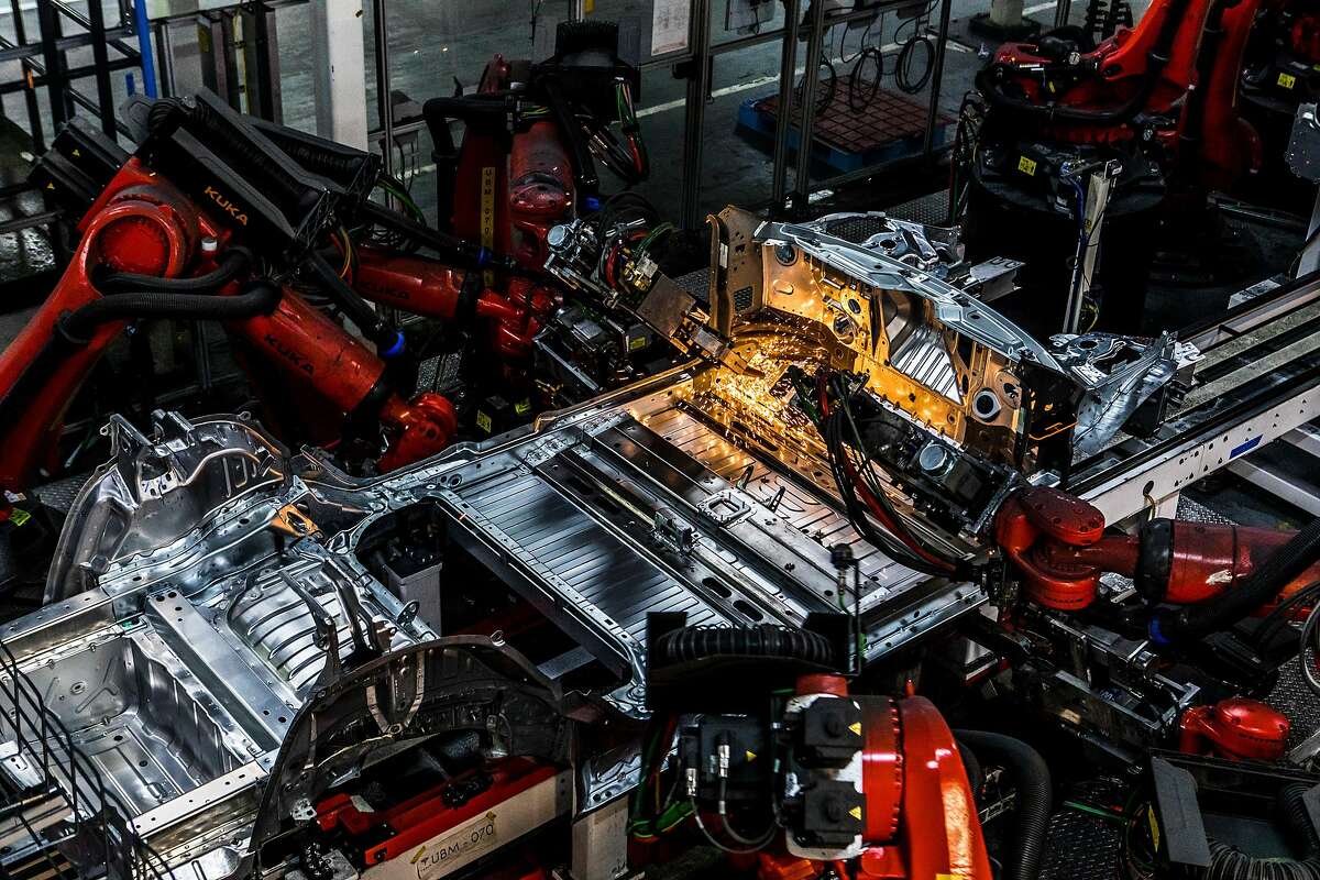 FILE -- Robot arms weld parts of a Tesla Model 3 at the company's factory in Fremont, Calif., June 14, 2018. A large part of the Tesla factory in Fremont is made up of large robot arms behind plexiglass. All welding has been automated for precision as well as employee safety. (Christie Hemm Klok/The New York Times)