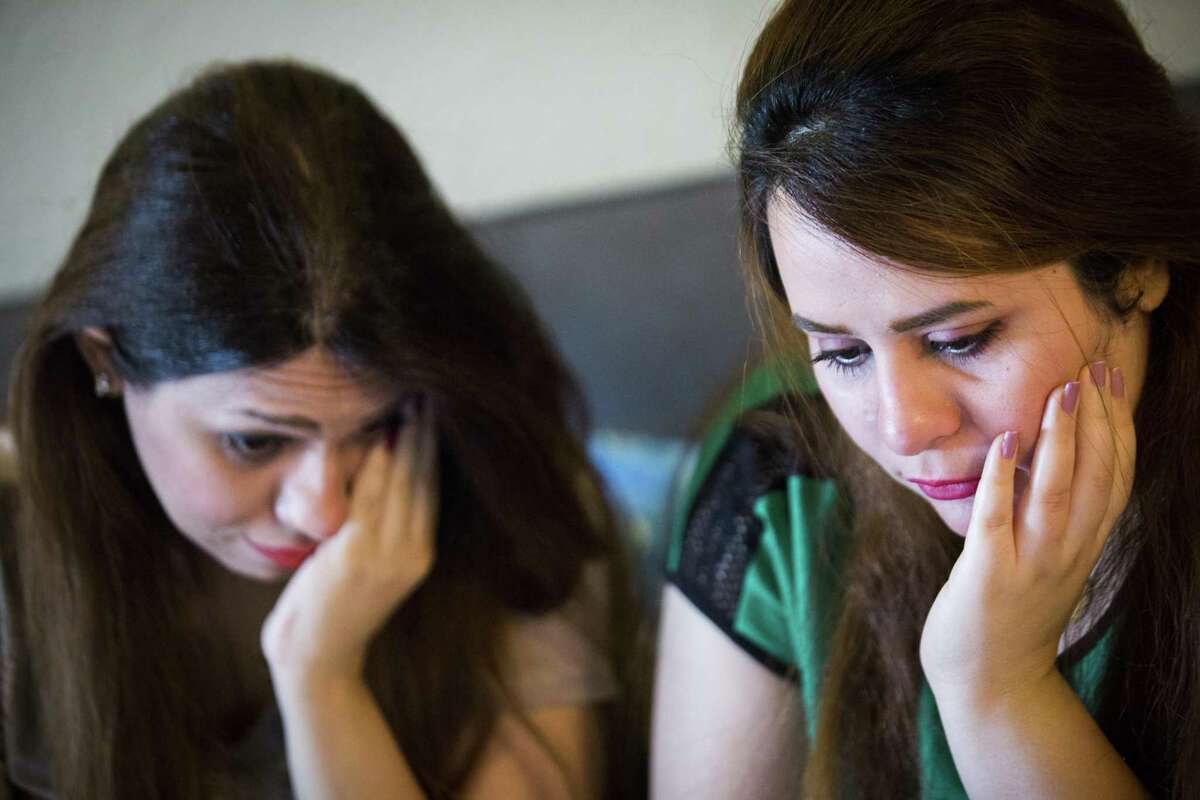 Sarah Ismaeil, left, 31, and her sister Dhuha Ameri, 26, hold back tears back while they speak with their parents living in Iraq using a video chat application, Tuesday, Aug. 28, 2018, in Houston. The sisters have been waiting for two years for their parents to be able to join them in the United States. Sarah, a doctor, and Dhuha, a pharmacist, said their family was harassed and threatened because of her sister's job working as an engineer with the U.S. military. The entire family applied for refugee status and everyone was granted the protection, except, their parents' applications stalled.