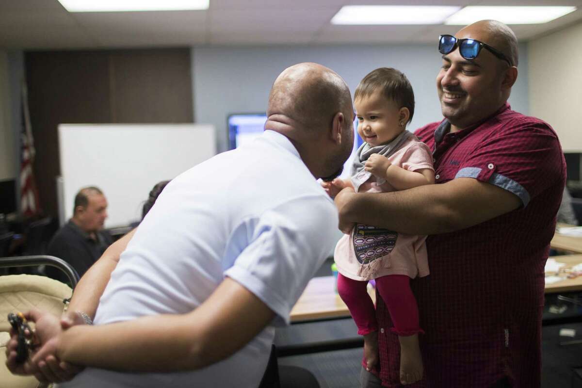 Ali Mohammed Saeed holds his 11-month-old daughter Sofia Saeed Ali while their neighbor plays with her minutes before an orientation for new comers at the YMCA International, Tuesday, Aug. 28, 2018, in Houston.