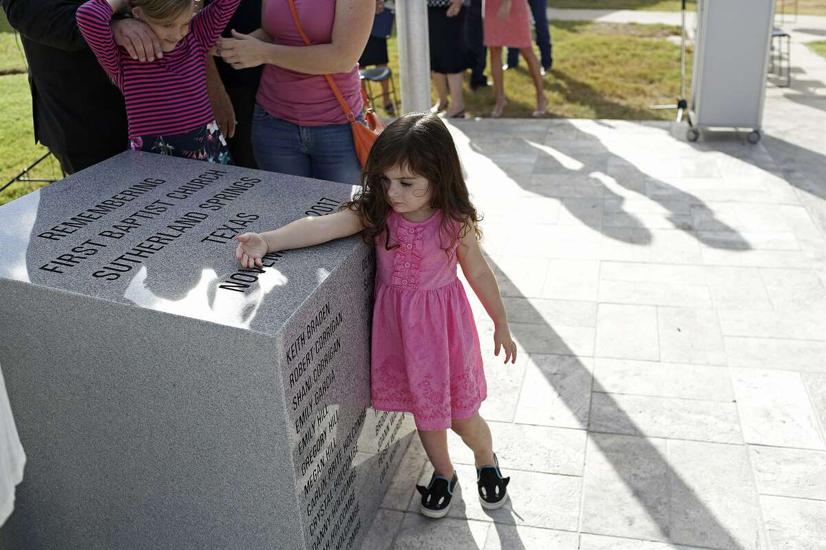 Elene Slavin, 3, a member of the Holcombe family, touches the memorial dedicated to the victims of First Baptist Church of Sutherland Springs. At left is Evelyn Hill, 8, also a member of the Holcombe family.