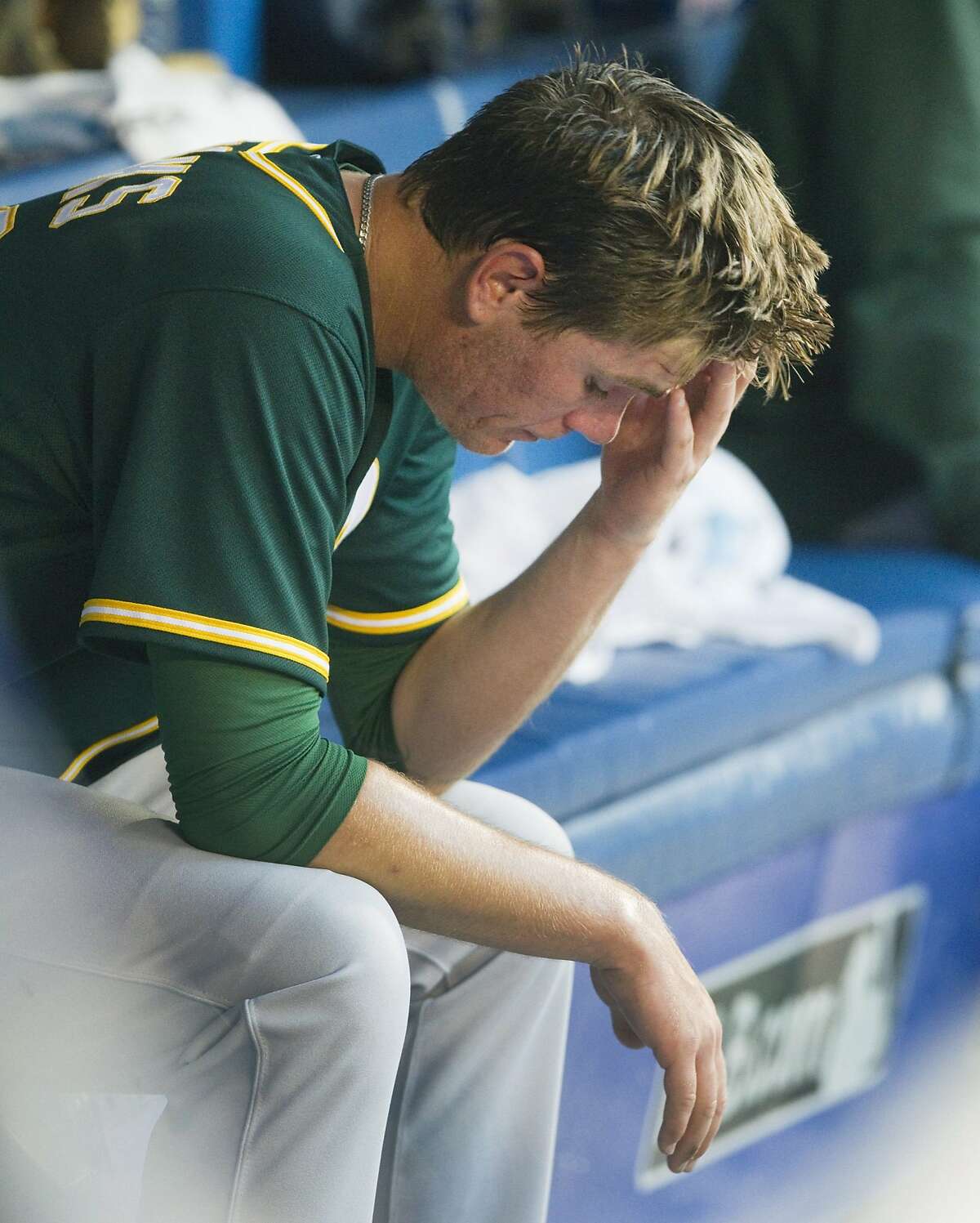 Oakland Athletics starting pitcher Aaron Brooks sits on the bench after being taken out of the baseball game against the Toronto Blue Jays during the second inning in Toronto on Wednesday, Aug. 12, 2015. 