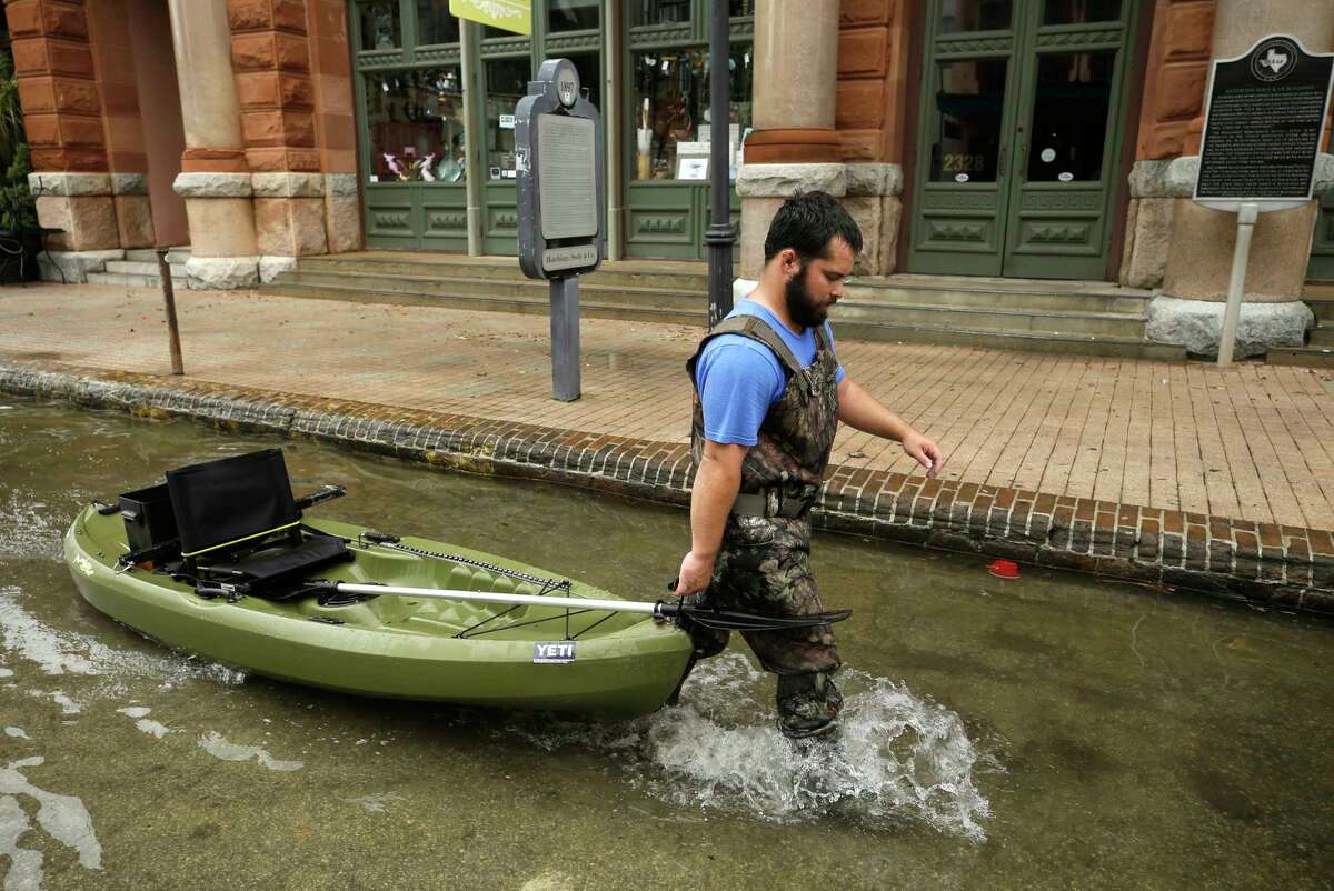 Tyler Hatfield pulls his boat along The Strand Monday, Sept. 3, 2018, in Galveston. He said he was sightseeing and he paddled along the street until the water became too shallow.