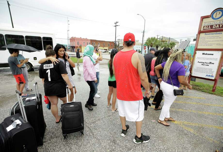 Carmen Martinez, second from left, hugs her niece, Erika Lara, both of Houston, as they wait in line to pay for parking before boarding a cruise ship for a five day vacation Monday, Sept. 3, 2018, in Galveston. Due to flooding, they were not able to get the regular cruise ship parking lots and had to park in a daily parking lot near The Strand. People waited in a long line to pay as they had to make a seperate credit card transaction for each day. Photo: Melissa Phillip, Staff Photographer / © 2018 Houston Chronicle