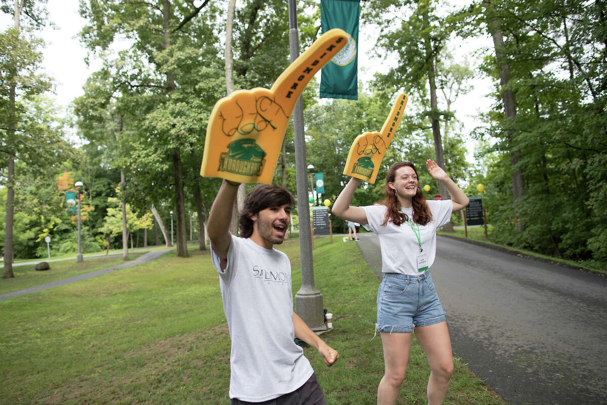 Skidmore peer helpers, Adam Simon, left, and Edin Gallaghar greet first-year students and their families near the entrance to Skidmore College on Aug. 30, 2018.