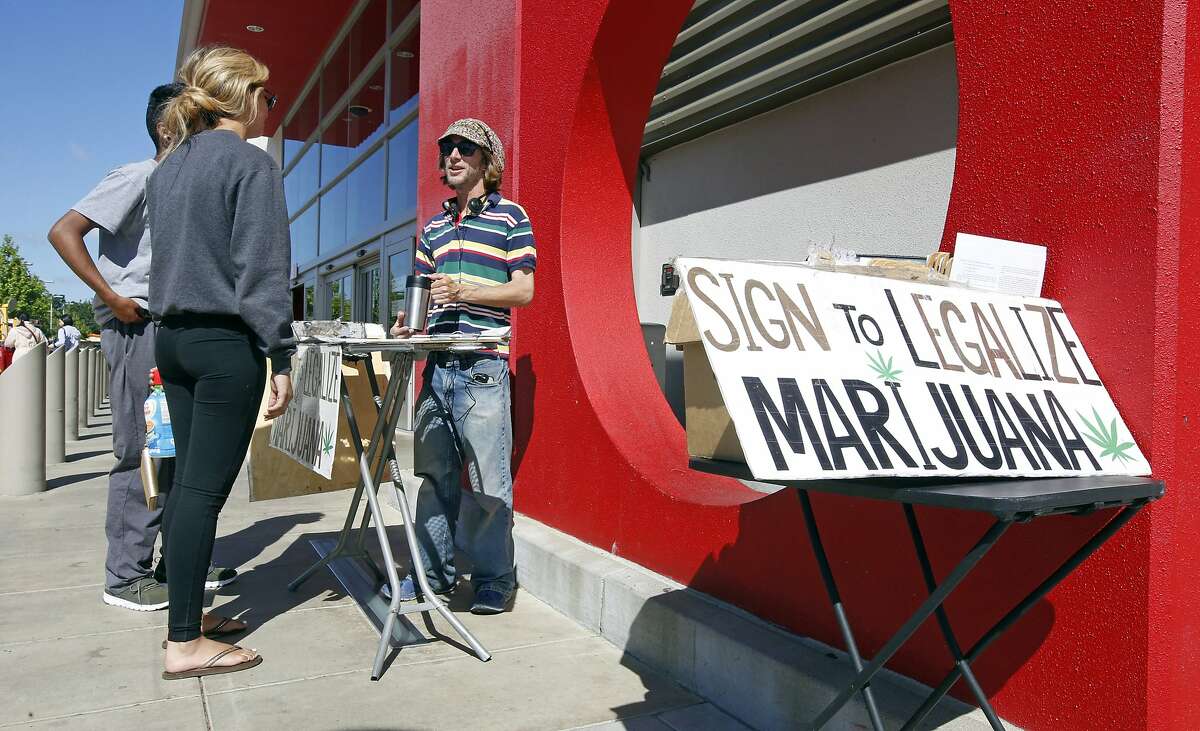 FILE - In this Saturday April 23, 2016, file photo, petition signature gatherer Peter Keyes, right, discusses a petition to legalize marijuana in Sacramento, Calif. The California state Senate approved a bill, Thursday, Aug. 23, 2018, to ban paying people based on the number of signatures they collect to place initiatives on the ballot. The measure, approved on a 25-14 vote, was sent to Gov. Jerry Brown who vetoed similar measure in 2011. (AP Photo/Rich Pedroncelli, File)