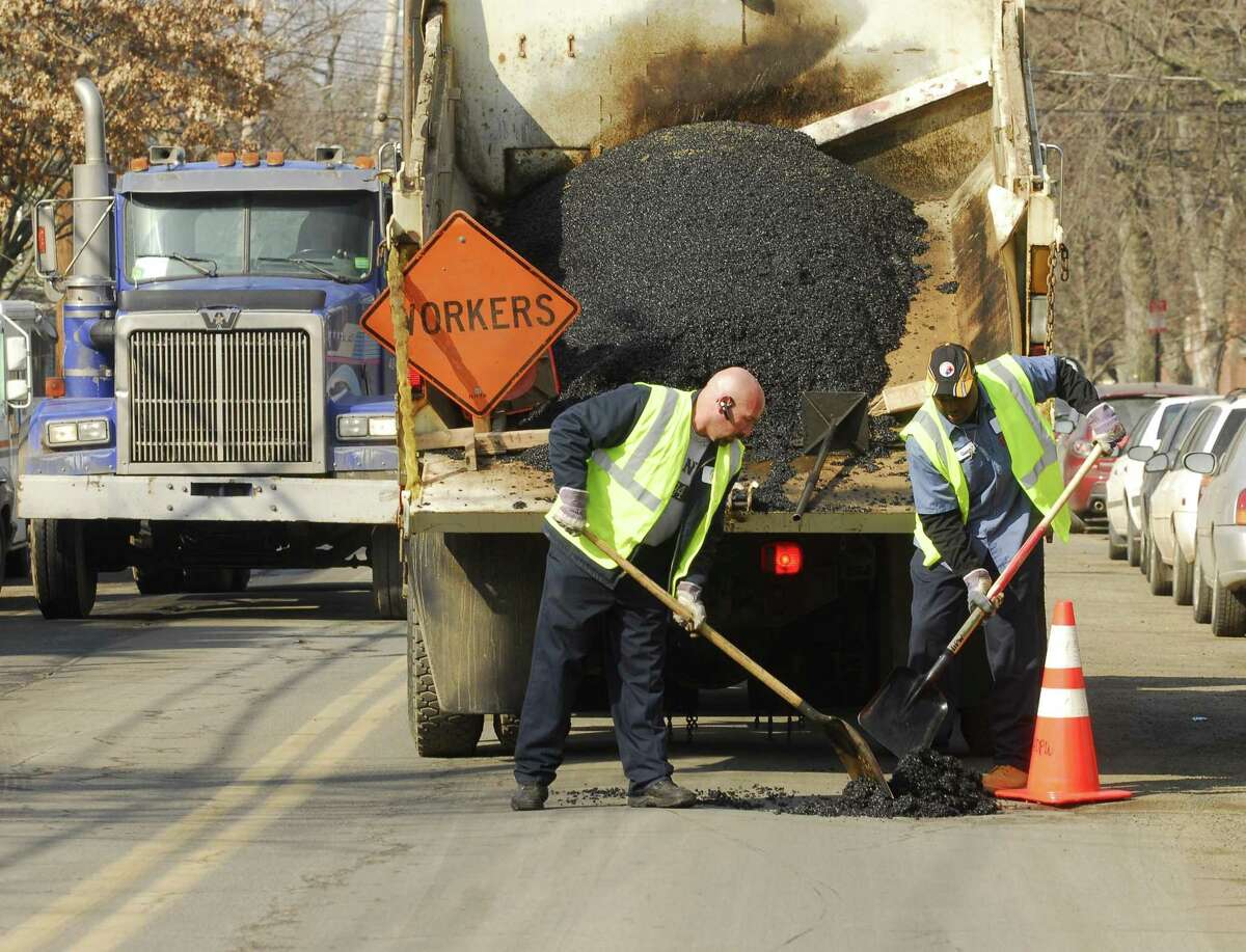 New Haven Department of Public Works employees fill a pothole on Humphrey Street near State Street with cold patch, an asphalt pavement repair material that quickly hardens after application.