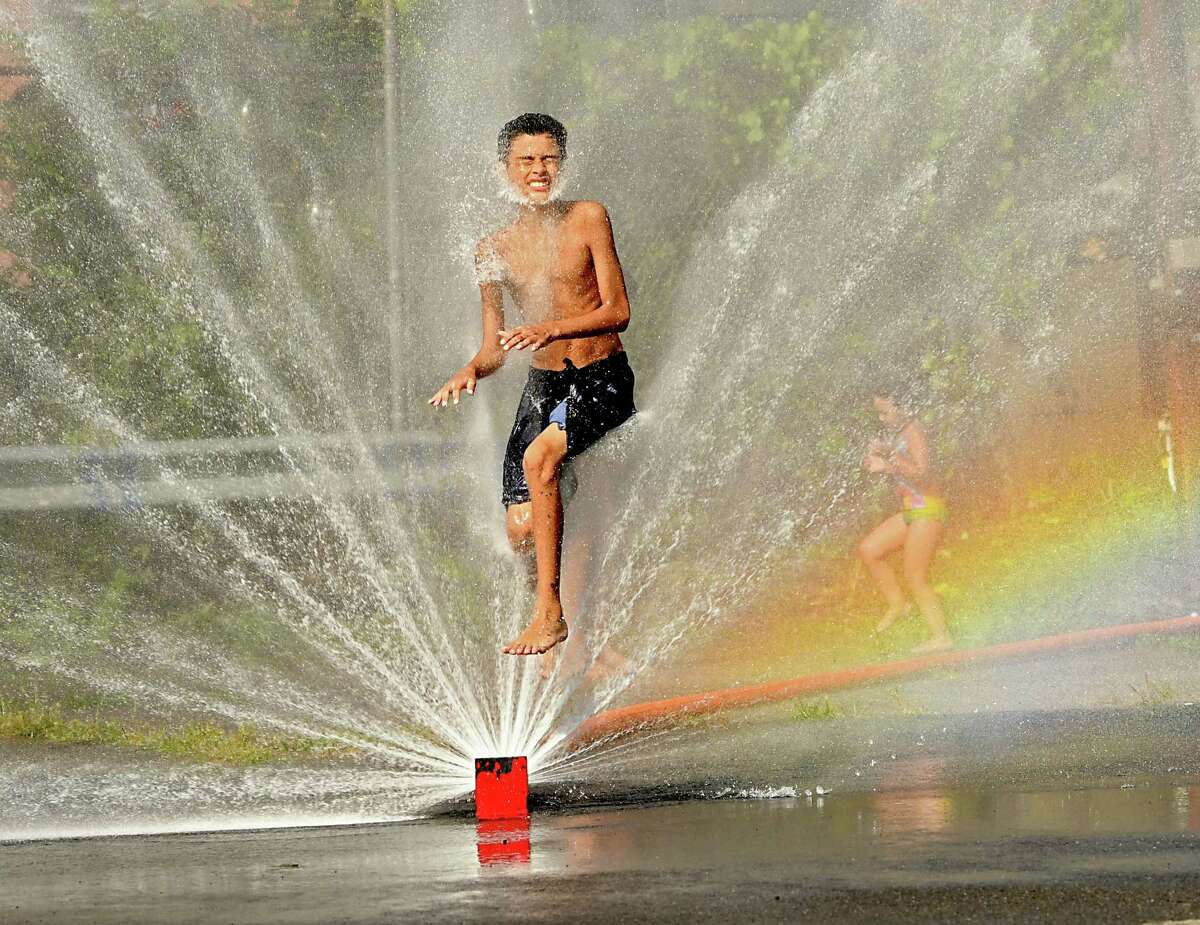 Jacob Garcia, 13, of Troy jumps through a the spray of a hose at a cooling station at the Little Italy Market Place on Liberty St. on Wednesday, Sept. 5, 2018 in Troy, N.Y. Temperatures hit the 90's today. (Lori Van Buren/Times Union)
