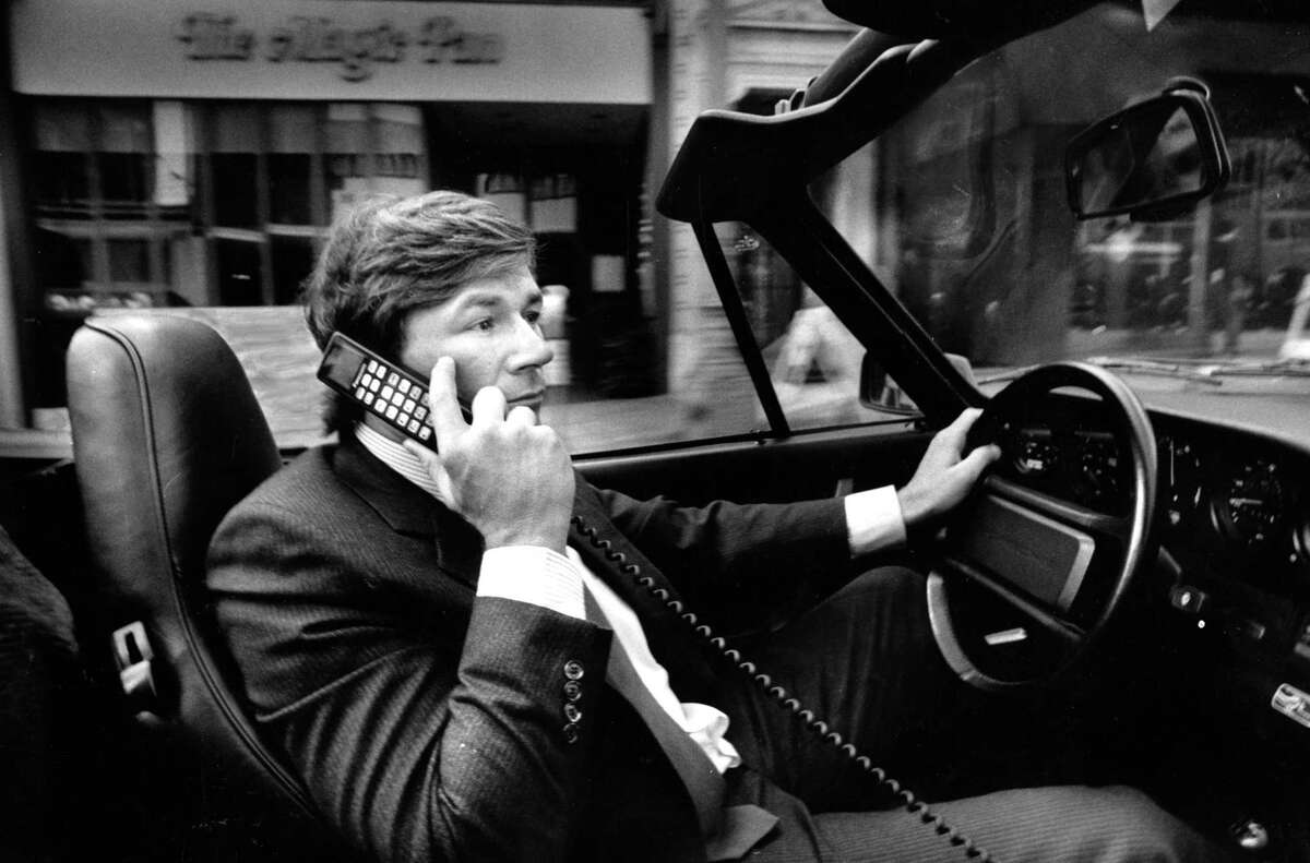 投资银行家迈克尔·扬西在保时捷里使用他的手机。1987年9月28日。