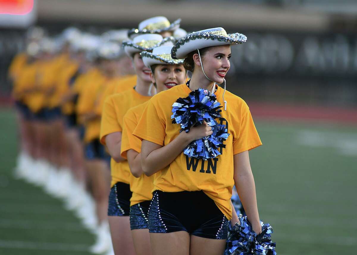 Captain Lauren Lackey, from right, a junior, and Brooke Rogers, a freshman, and the Kingwood Fillies, stand in formatiion for the playing of the National Anthem before kickoff of the Mustang's football season home opener versus Dekaney at Turner Stadium in Humble on Sept. 6, 2018. The gold shirts, worn by the Fillies and KHS students, parents and fans, were printed with "Gold...Fight...Win" (Fighting Childhood Cencer Together) to represent the mantra of the school's fundraiser in support of Addi's Faith Foundation, Mothers Against Cancer and the L3 Foundation.